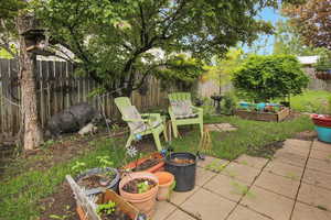Fenced backyard with a vegetable garden and a patio