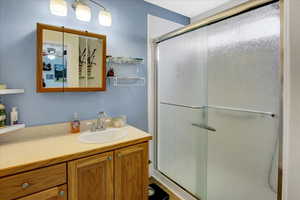 Full bath featuring vanity, a shower stall, and a ceiling fan