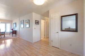 Unfurnished room with a chandelier, light wood-style floors, baseboards, and a textured ceiling