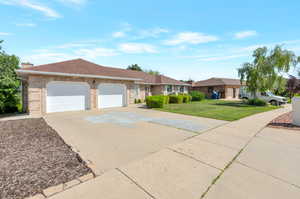 Ranch-style home featuring an attached garage, concrete driveway, a front lawn, roof with shingles, and brick siding