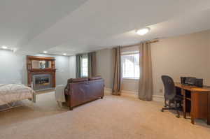 Bedroom with carpet floors, a glass covered fireplace, an office area, recessed lighting, and baseboards