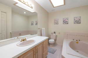Full bathroom featuring tile patterned flooring, a bath, vanity, toilet, and baseboards