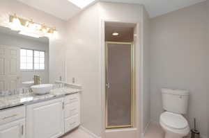 Full bath with vanity, a stall shower, baseboards, toilet, and tile patterned floors