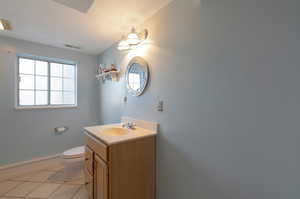 Bathroom featuring toilet, vanity, baseboards, and tile patterned flooring