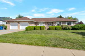 Ranch-style house with a garage, concrete driveway, a front lawn, and brick siding