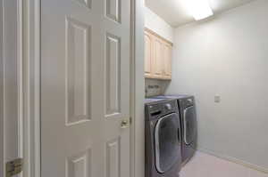 Laundry area featuring washing machine and clothes dryer, cabinet space, and light tile patterned floors