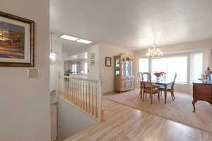Dining room featuring wood finished floors, a chandelier, baseboards, and a textured ceiling