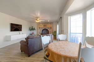 Dining room featuring a ceiling fan, light wood finished floors, a brick fireplace, and baseboards