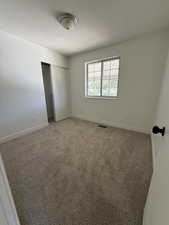Unfurnished bedroom with baseboards, a closet, a textured ceiling, and light carpet