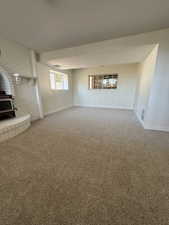 Unfurnished living room featuring a wood stove, baseboards, and carpet floors