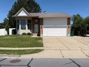 View of front of property with a garage, brick siding, concrete driveway, and metal roof
