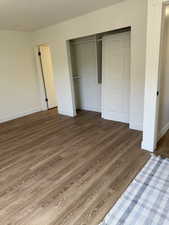 Unfurnished bedroom with a closet, wood finished floors, and baseboards