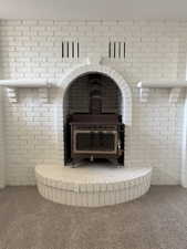 Detailed view of a wood stove, carpet, and brick wall