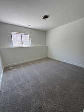 Unfurnished room featuring a textured ceiling, baseboards, and carpet