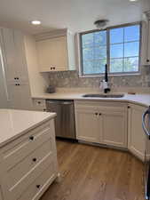 Kitchen with dishwasher, a sink, light wood-style flooring, healthy amount of natural light, and a textured ceiling