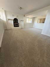 Unfurnished living room with baseboards, carpet floors, and brick wall