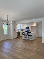 Kitchen featuring stainless steel appliances, baseboards, wood finished floors, a chandelier, and a textured ceiling