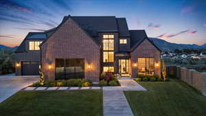 View of front facade featuring a standing seam roof, brick siding, board and batten siding, and concrete driveway