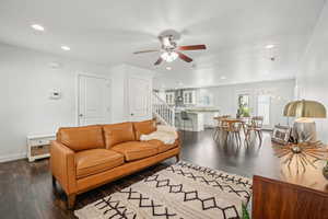 Living area with dark wood-style flooring, a ceiling fan, recessed lighting, stairs, and baseboards