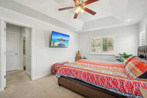 Primary bedroom with a raised ceiling, baseboards, ceiling fan, recessed lighting, and arched walkways