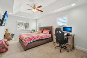 Primary bedroom with a raised ceiling, recessed lighting, a desk, baseboards, and ceiling fan