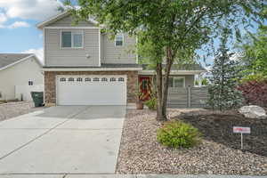 View of front of home featuring concrete driveway, a garage, and stone siding