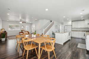Dining space featuring recessed lighting, ceiling fan, stairs, dark wood-style flooring, and a large island