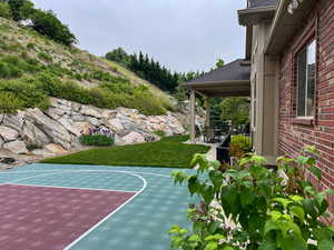 View of sport court with basketball hoop and a lawn