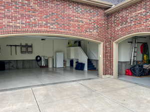 3 car garage featuring freestanding refrigerator and driveway