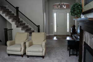 Entryway with a chandelier, stairs, and carpet floors