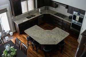 Kitchen with stainless steel appliances, a sink, backsplash, and dark wood-style flooring