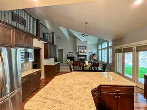 Kitchen featuring stainless steel appliances, a ceiling fan, dark brown cabinetry, high vaulted ceiling, and dark wood-style floors