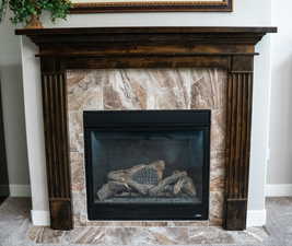 Detailed view of a fireplace, carpet floors, and baseboards