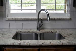 Kitchen view of a sink, tasteful backsplash, and light stone counters