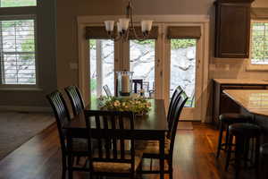 Dining space with a chandelier, dark wood-style floors, and baseboards