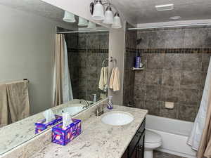Full bathroom featuring vanity, a textured ceiling, shower / tub combo with curtain, and toilet