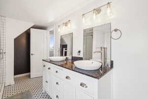 Bathroom with double vanity, tile patterned floors, and a tile & glass shower