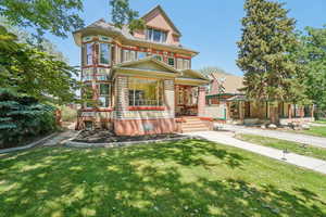Victorian-style house with a porch, a front yard, and brick construction
