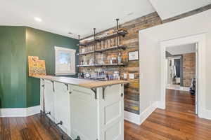 Indoor dry bar featuring dark wood floors, baseboards, wood walls, and recessed lighting