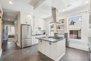 Gourmet Kitchen with stainless appliances, island range hood, a sink, dark countertops, and white cabinets
