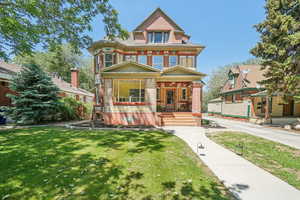 View of front facade featuring a porch, brick, and front lawn