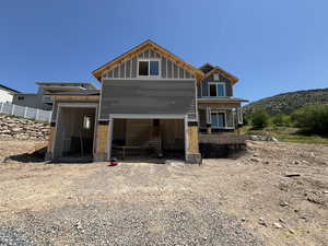 Back of property with a garage, a mountain view, stairway, and gravel driveway