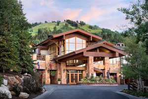 View of front of home with stone siding, french doors, and a balcony