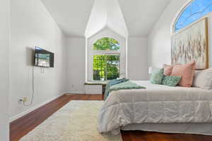 Bedroom with lofted ceiling, wood finished floors, and baseboards