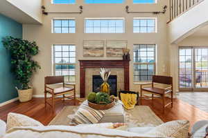 Living room with a towering ceiling, hardwood / wood-style floors, a fireplace, arched walkways, and baseboards