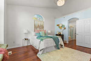 Bedroom with arched walkways, wood finished floors, lofted ceiling, and baseboards