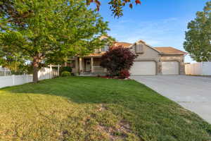 View of property hidden behind natural elements featuring stucco siding, concrete driveway, an attached garage, covered porch, and stone siding