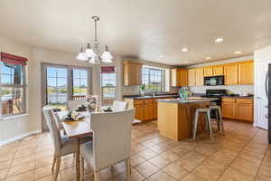 Kitchen with black microwave, a center island, a chandelier, recessed lighting, and light tile patterned floors