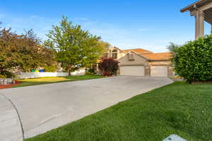 View of front of home featuring stucco siding, driveway, a front yard, and a garage