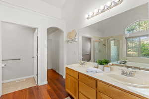 Full bathroom with a shower stall, a bath, double vanity, and wood finished floors